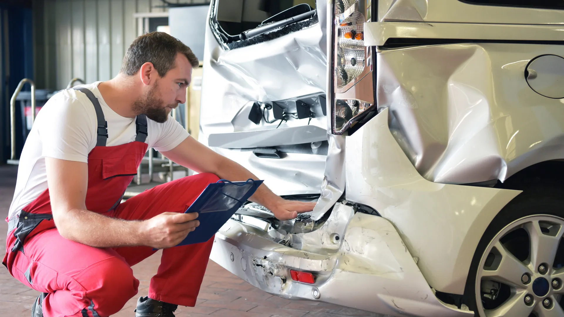 Mechanic assesses the accident damage to a van Mechanic assesses the accident damage to a van