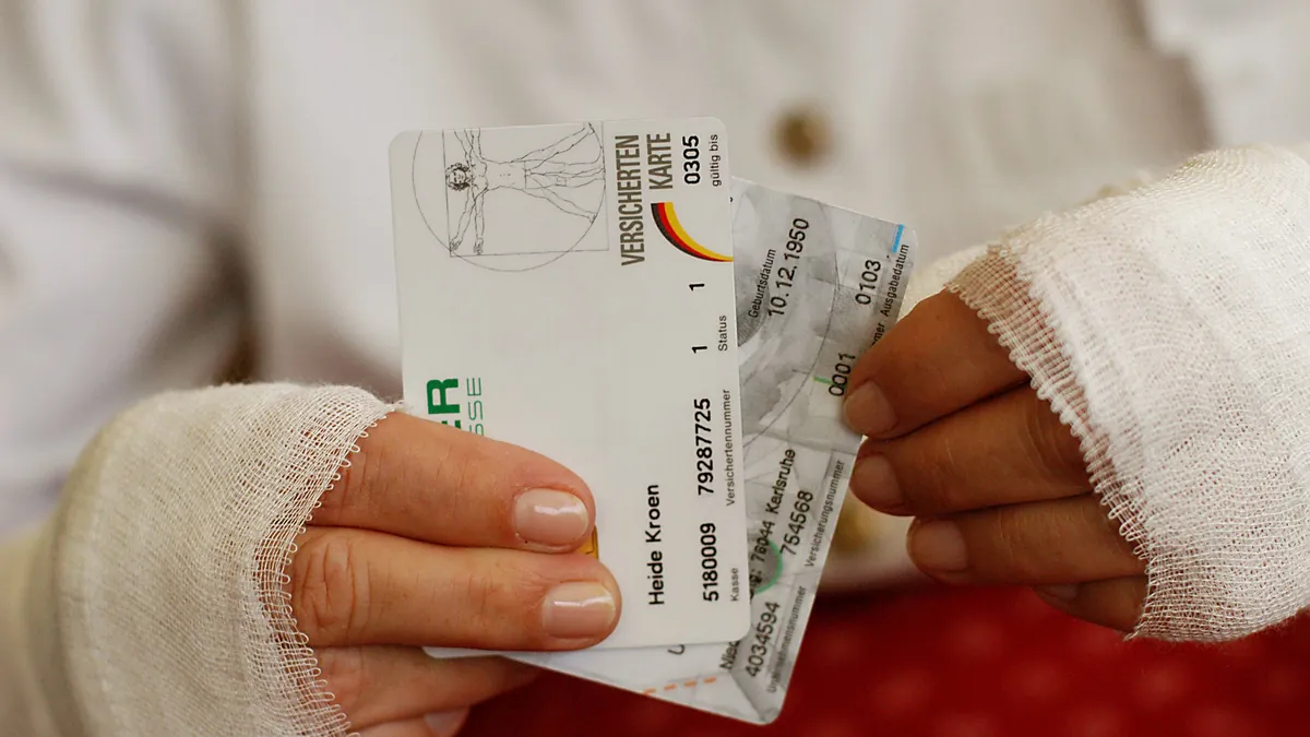 Verbundene Hände mit Krankenkassenkarten: Aufgrund falscher Angaben hat eine Krankenkasse einem Versicherten wieder gekündigt.